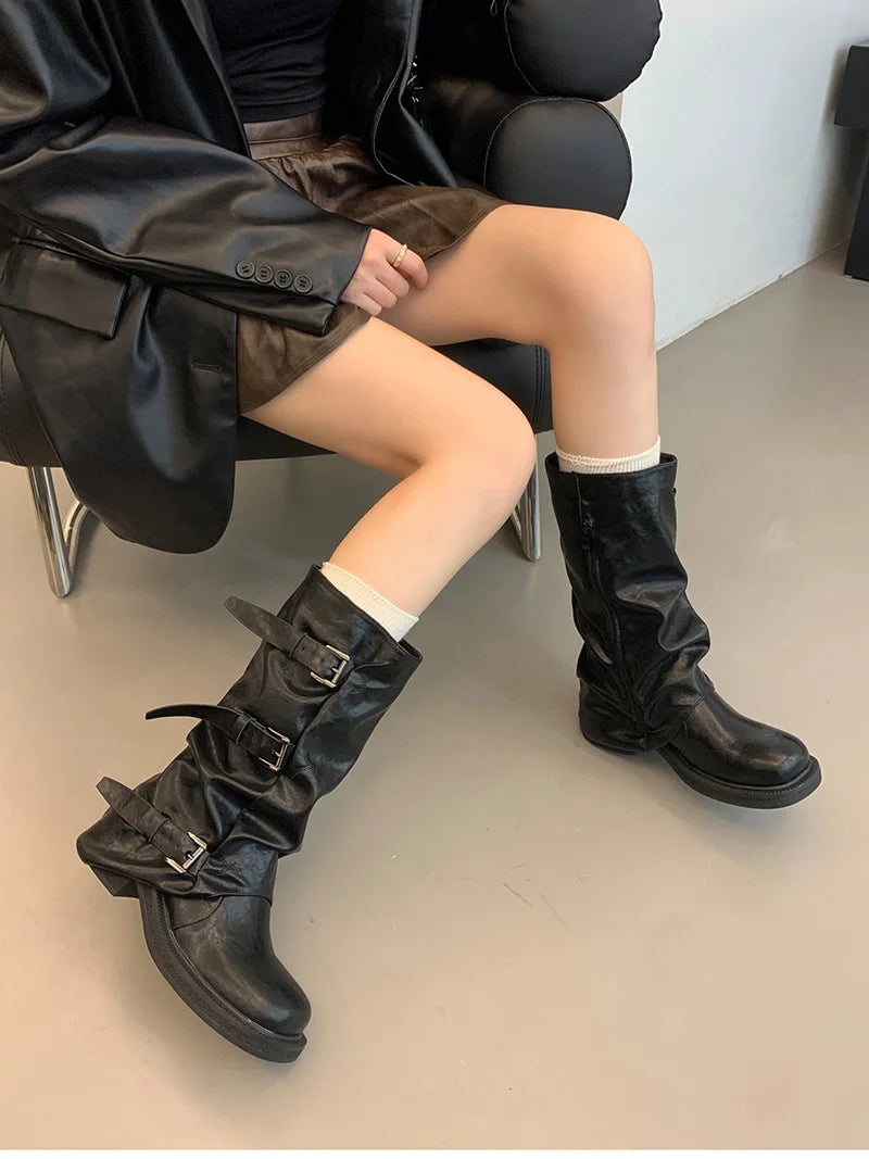 Person wearing black knee-high boots sitting on a chair.