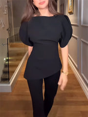 Person wearing a black outfit with puffed sleeves in an indoor setting