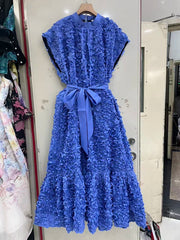 Blue lace dress with a belt on a hanger against a white wall.