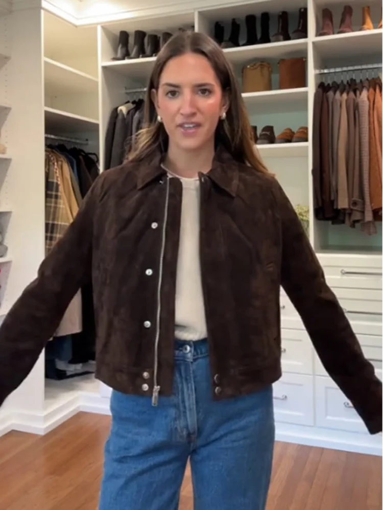Woman wearing a brown jacket and blue jeans in a clothing store.