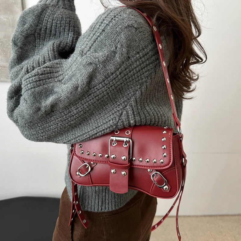 Person wearing a gray sweater with a red studded handbag.