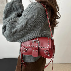 Person wearing a gray sweater with a red studded handbag.