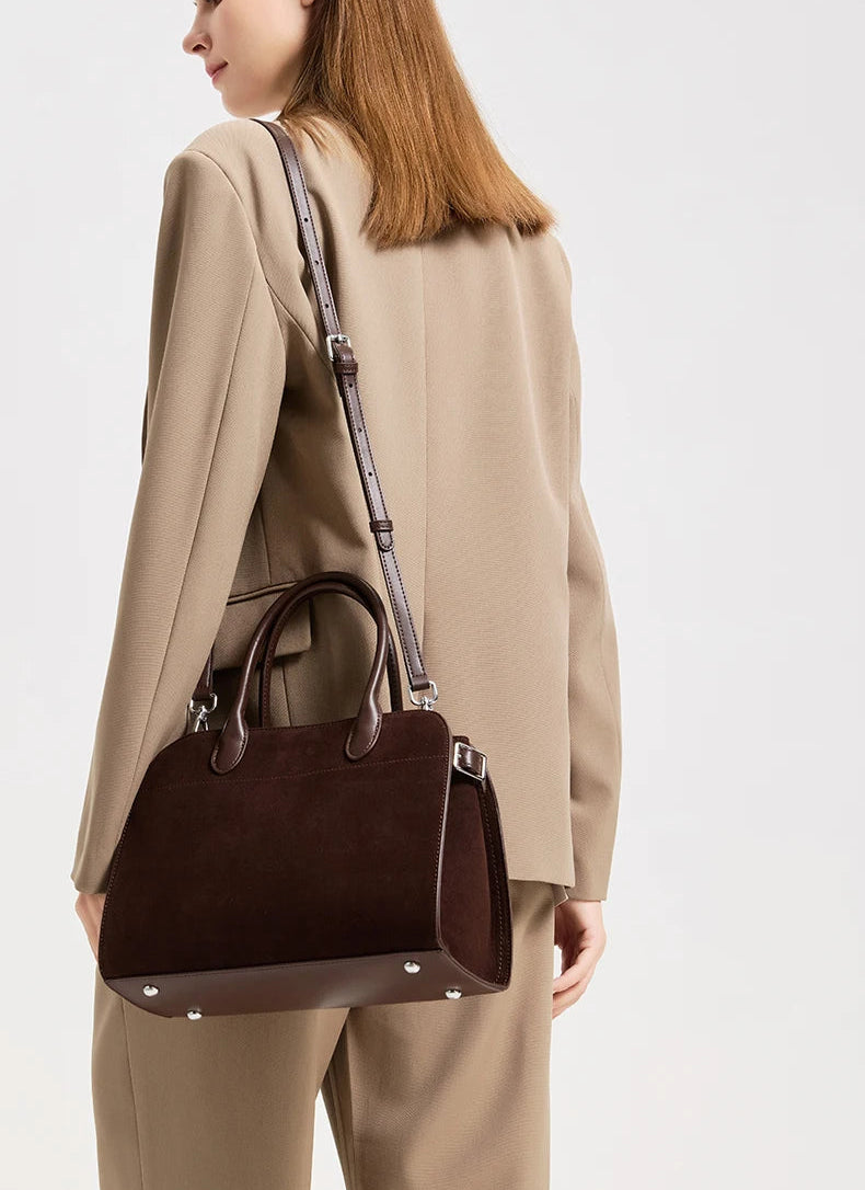 Woman holding a brown handbag against a white background