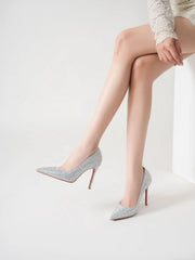 Silver high-heeled shoes with red soles worn by a person