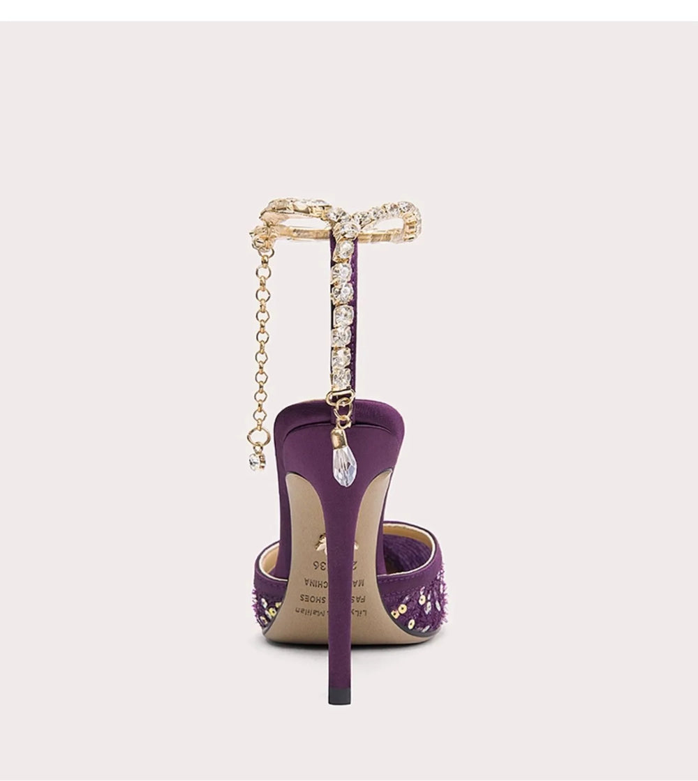 Purple high-heeled shoe with a gold ring and chain on a white background
