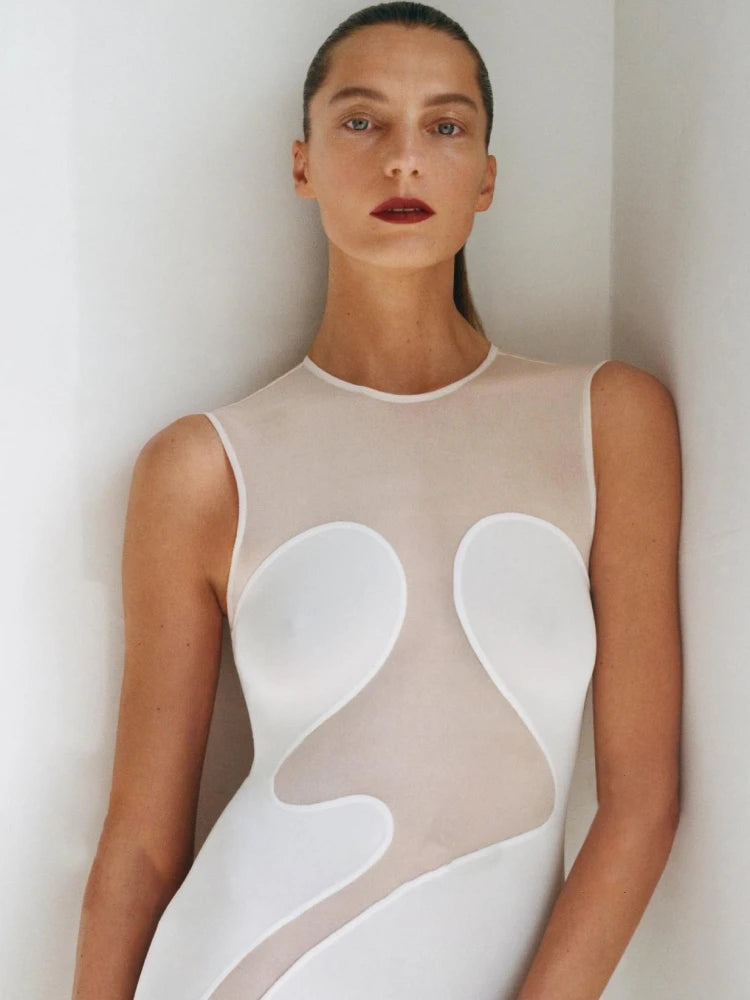 Woman wearing a sleeveless dress with abstract white patterns on a plain background