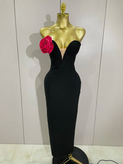 Black evening gown on a mannequin with a pink flower against a white wall