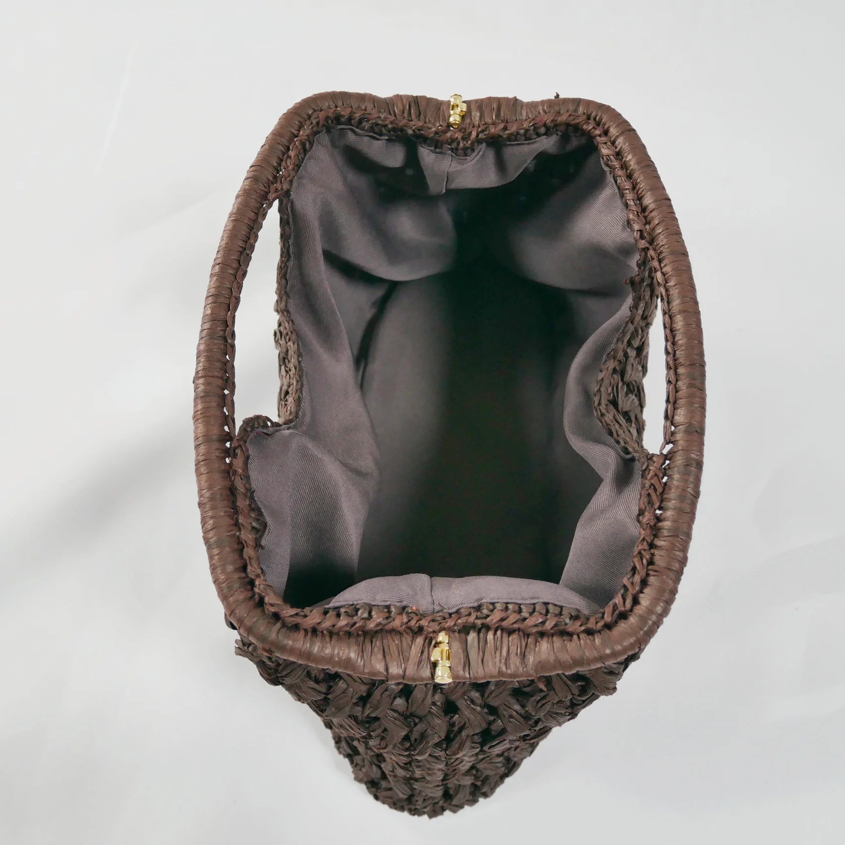 Brown woven handbag with gold zipper on a light gray background