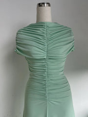 Green dress on a mannequin against a plain background