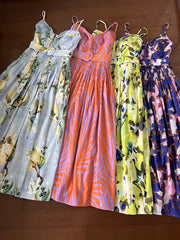Four floral-patterned dresses hanging on a brown background