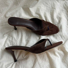 Pair of brown high-heeled sandals on a white textured surface