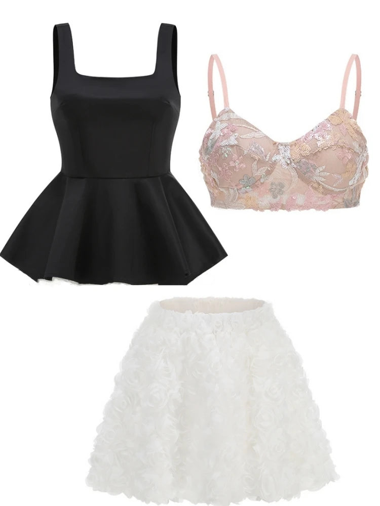 Black peplum top, pink lace bralette, and white ruffled skirt on a white background