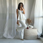 Woman in a white outfit posing in a room with white curtains and decor.