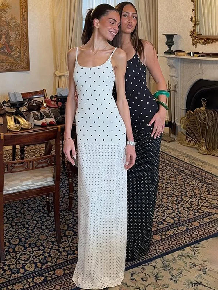 Two women in polka dot dresses standing in an elegant room with a fireplace and ornate decor.