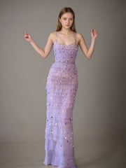 Woman wearing a lavender evening gown with beaded details against a plain background