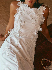 White lace dress worn by a person sitting on a textured surface.