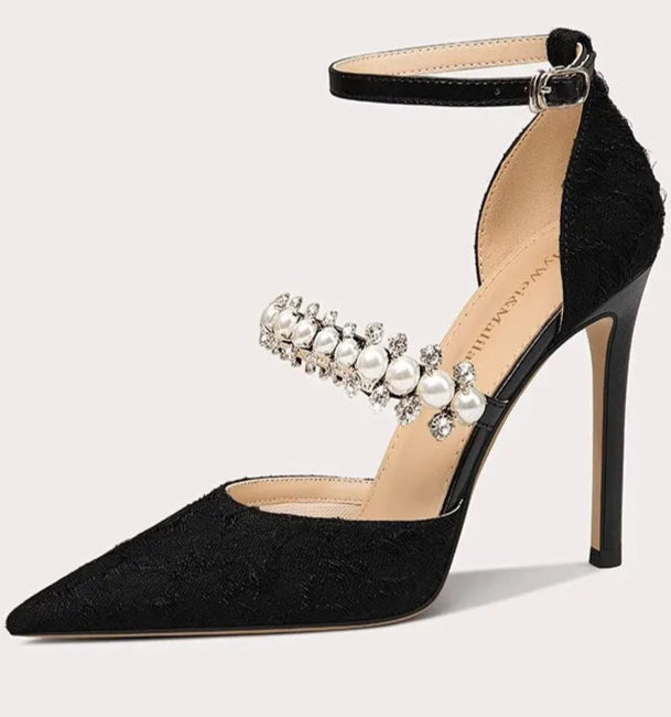Black high-heeled shoe with pearl embellishments on a white background