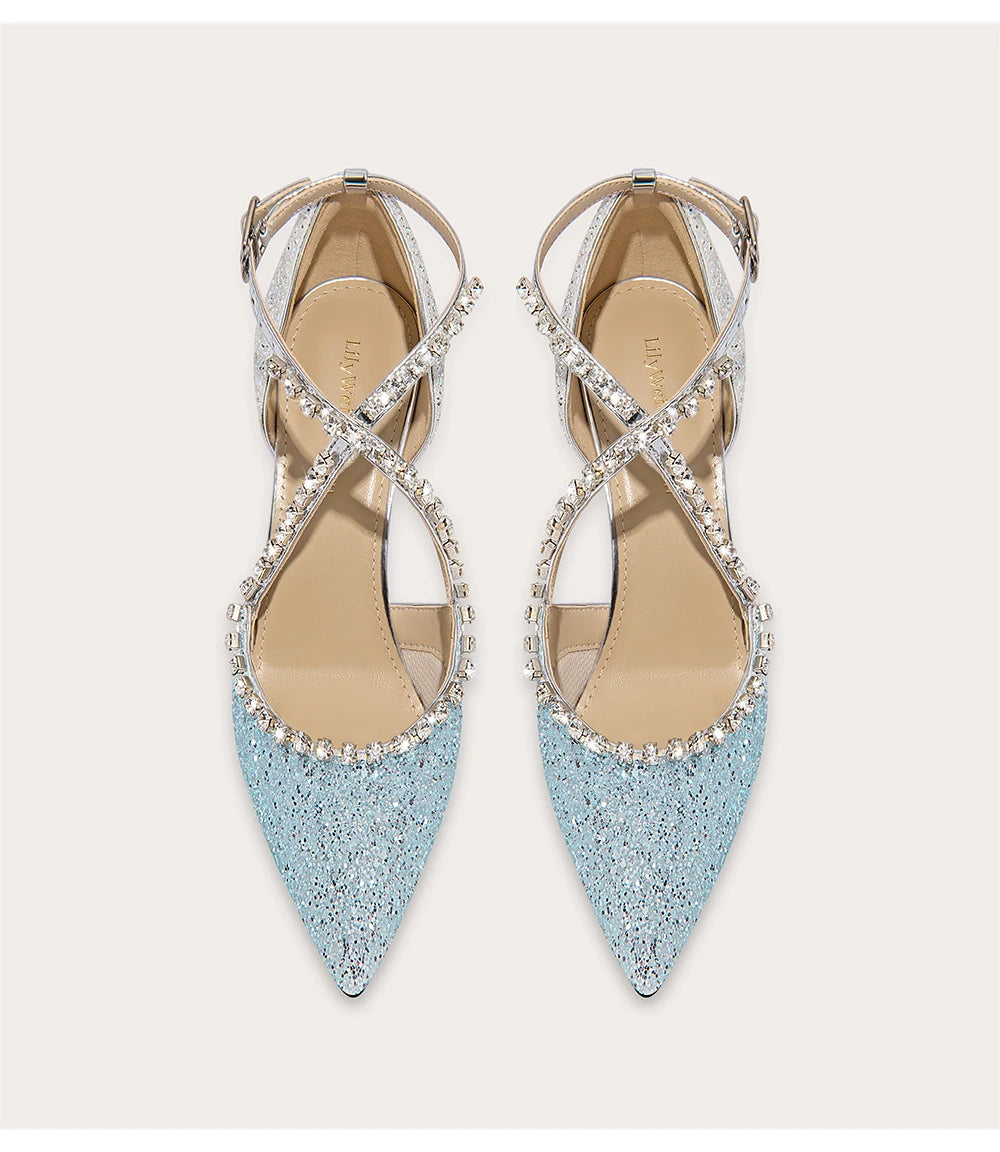 Pair of light blue pointed-toe shoes with criss-cross straps and rhinestone details on a white background.