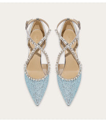 Pair of light blue pointed-toe shoes with criss-cross straps and rhinestone details on a white background.