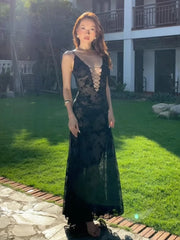 Woman in a black lace dress standing on grass with a building in the background