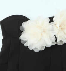 Black garment with large white floral embellishments on a light gray background