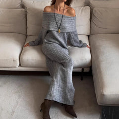 Person wearing a gray off-shoulder outfit sitting on a beige sofa.