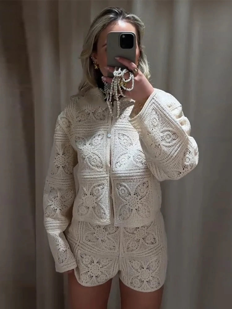 Person wearing a white crochet outfit taking a mirror selfie against a plain background