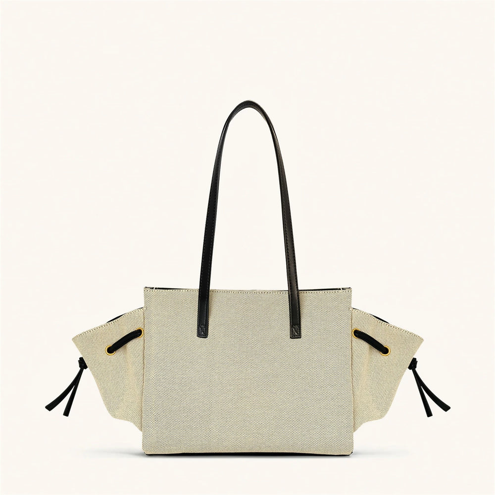 Beige tote bag with black handles and straps on a white background
