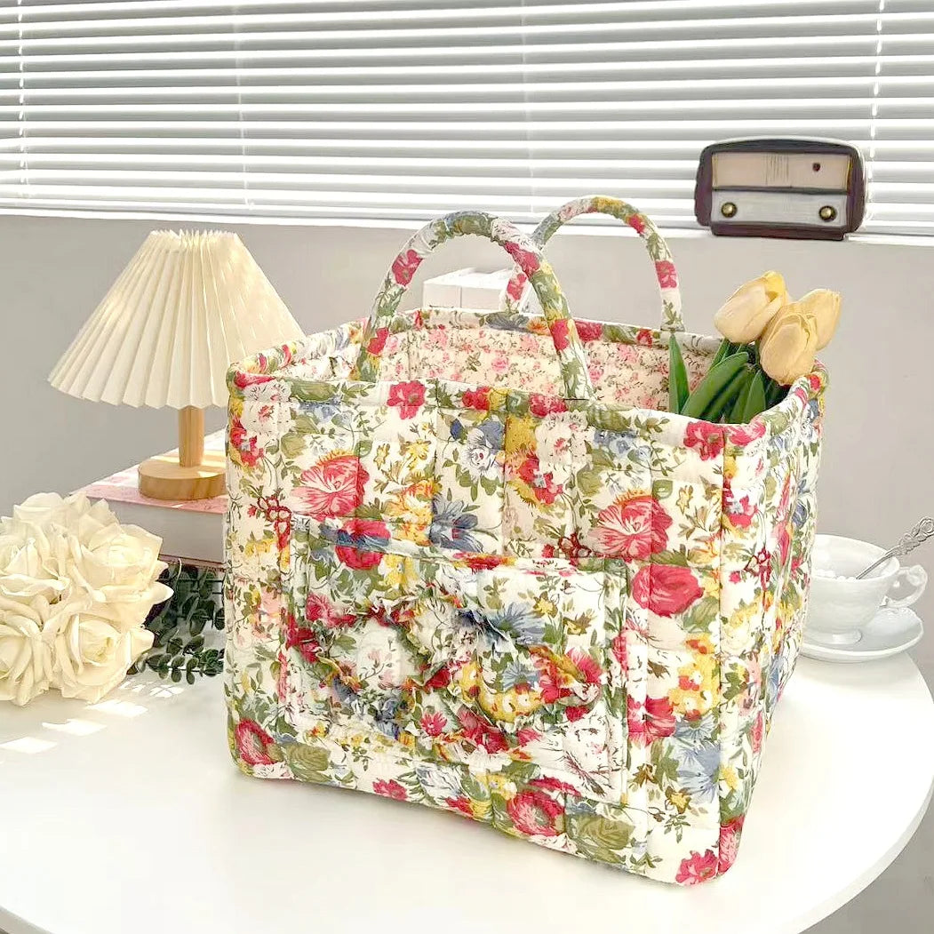 Floral patterned bag on a table with flowers and a lamp in the background
