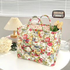 Floral patterned bag on a table with flowers and a lamp in the background