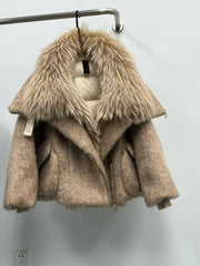 Beige coat with fur collar on a hanger against a white wall