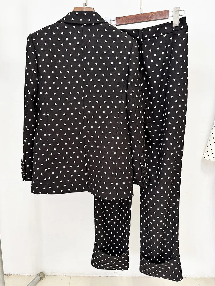 Back view of a black polka dot print blazer and trousers with a red bow detail on a hanger.