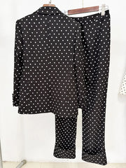 Back view of a black polka dot print blazer and trousers with a red bow detail on a hanger.