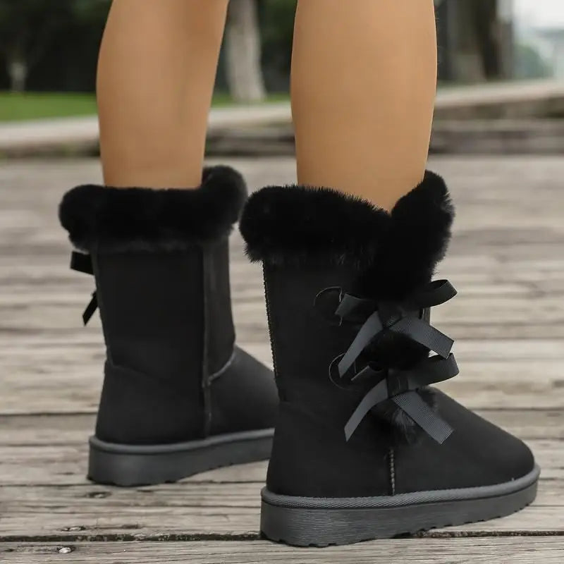 Black winter boots with fur trim on a wooden floor