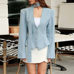 Person wearing a light blue blazer over a white outfit in an indoor setting.