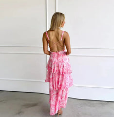 Woman wearing a pink tie-dye dress with criss-cross back design against a white wall.