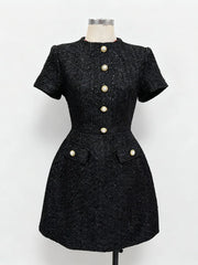 Black dress with pearl buttons on a mannequin against a white background