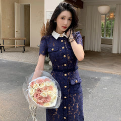Woman in a blue lace dress holding a bouquet of flowers indoors.