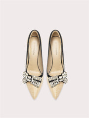 Pair of pointed-toe shoes with embellishments on a light gray background