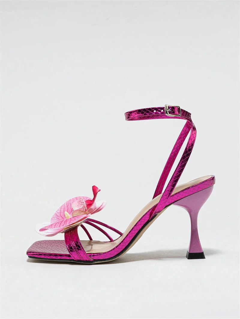 Pink high-heeled shoe with a decorative flower on a white background