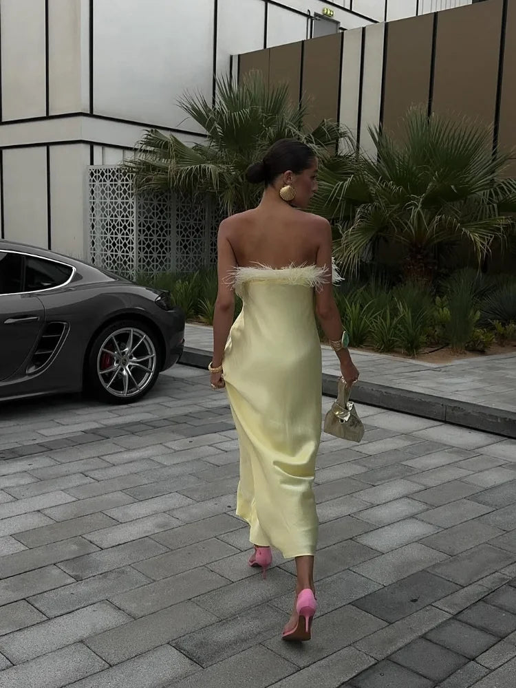 Woman in a yellow dress walking outdoors with a car and building in the background