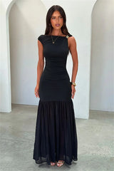 Woman wearing a black dress standing against a white architectural background