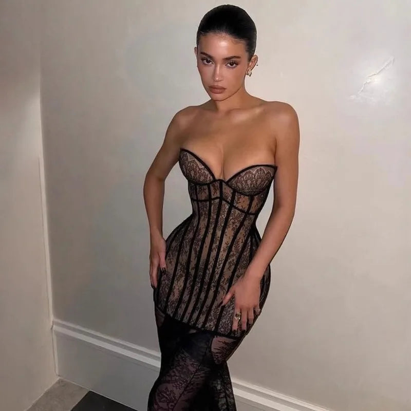 Woman wearing a black lace dress against a plain background