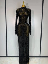 Black beaded evening gown on a mannequin against a white wall.