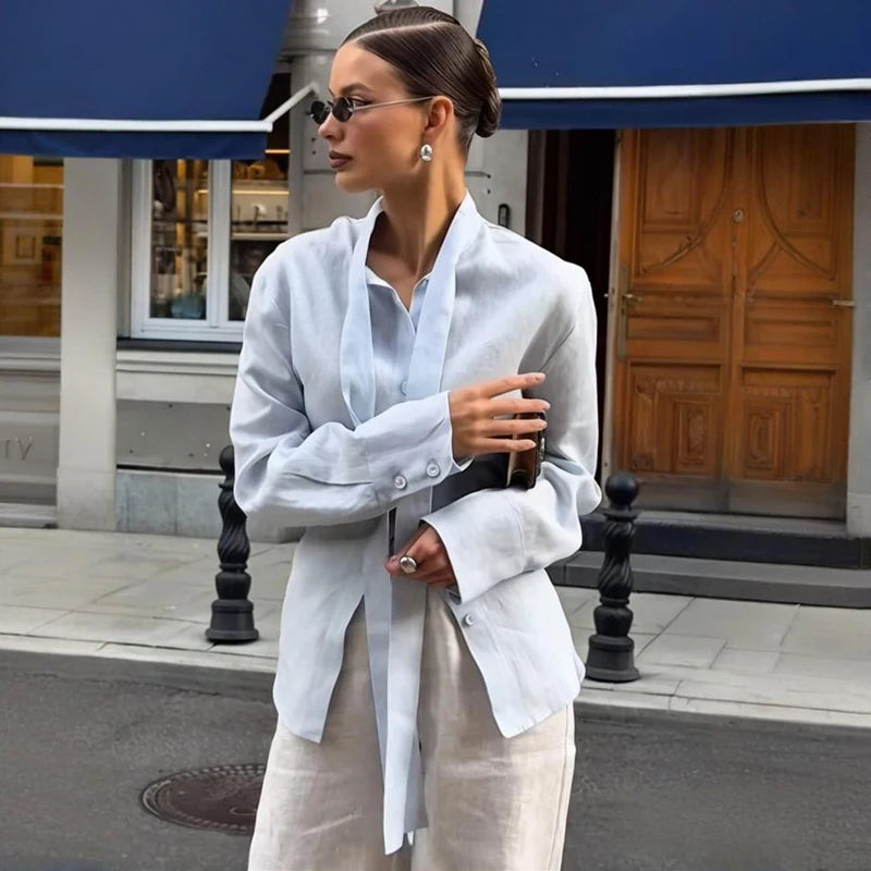 Woman in a white shirt and beige pants standing on a city street.