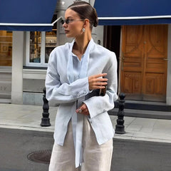 Woman in a white shirt and beige pants standing on a city street.