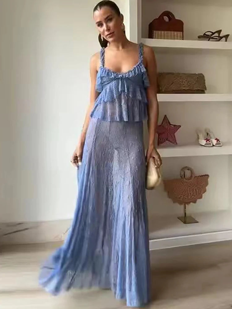 Woman wearing a blue dress standing in a room with shelves in the background