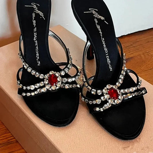 Black open-toe stiletto heels with red spider gem embellishments.