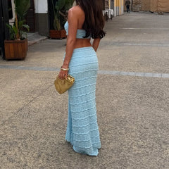 Woman in a blue outfit holding a gold clutch on a street.