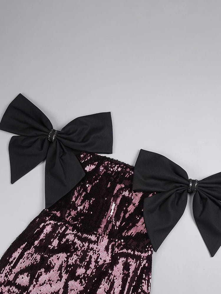 Pink sequin top with black bows on a gray background